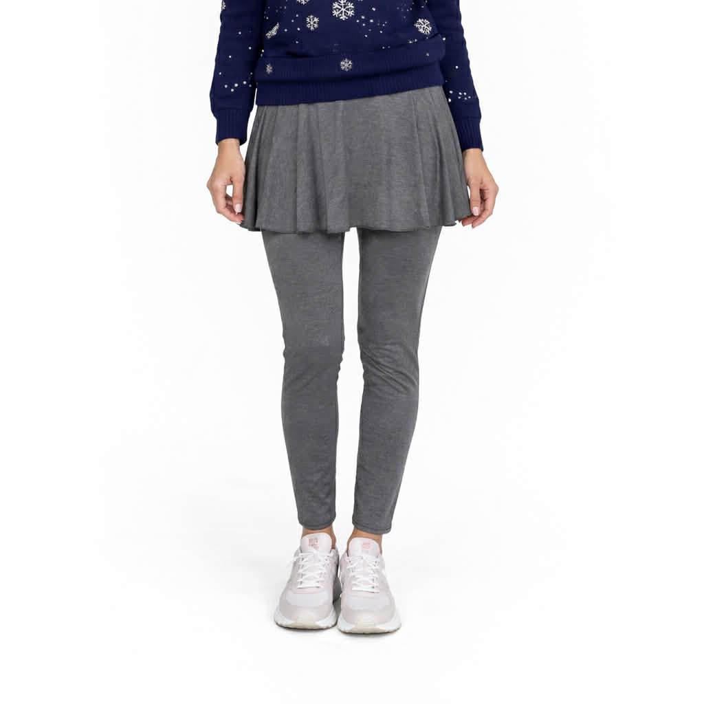 Person wearing a navy sweater with white patterns and gray pleated skirt and leggings on a white background
