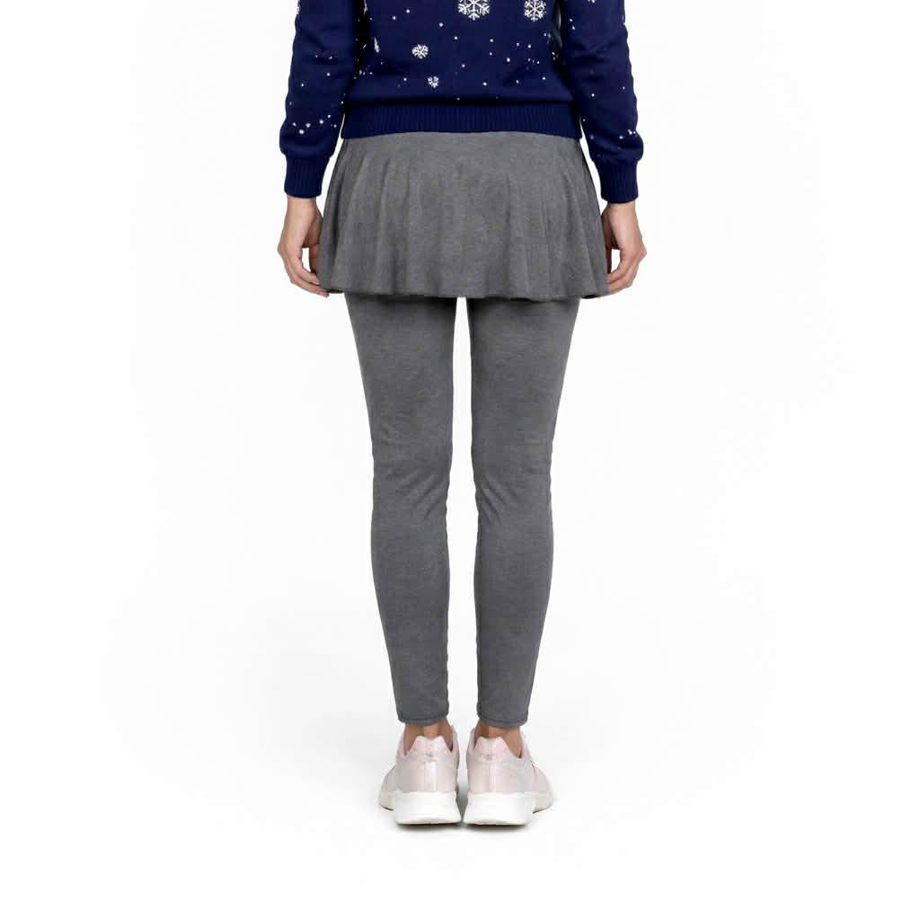 Person wearing a blue sweater with snowflake patterns, gray pleated skirt, and gray leggings on a white background