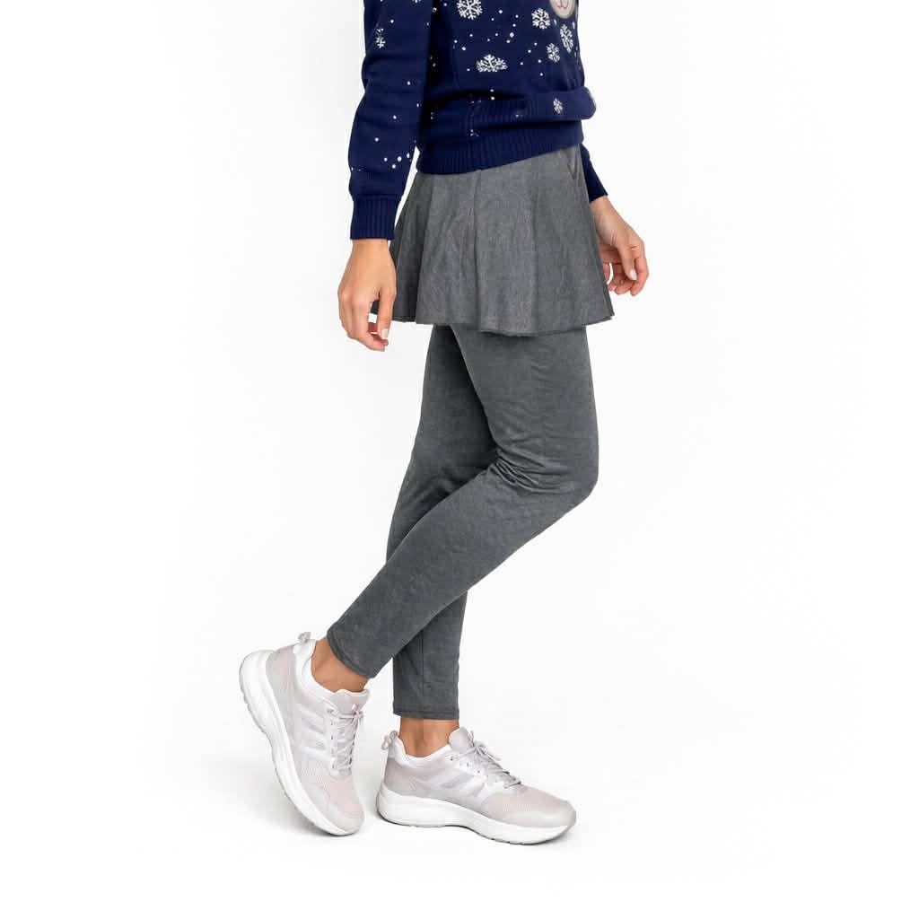 Person wearing a navy sweater, gray skirt, and gray jogger pants on a white background