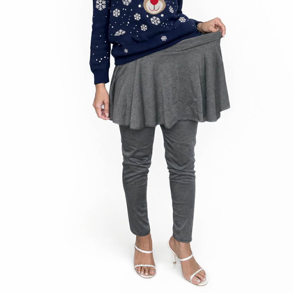 Person wearing a navy sweater with a reindeer design and gray skirt and leggings on a white background
