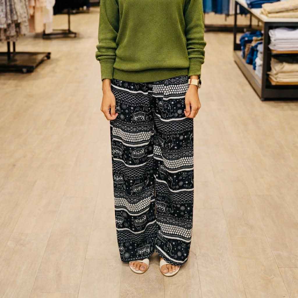Person wearing a green sweater and patterned black and white pants in a store setting
