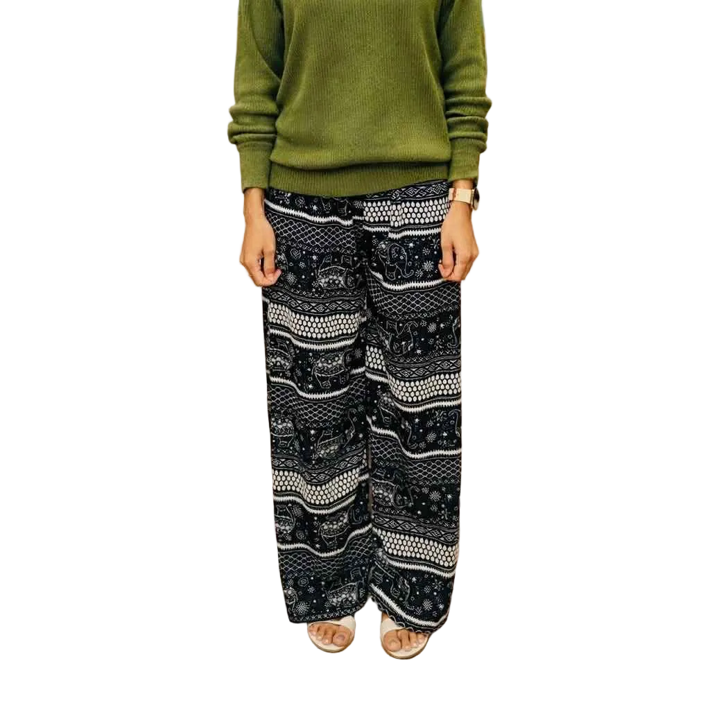 Person wearing a green sweater and black patterned pants on a white background