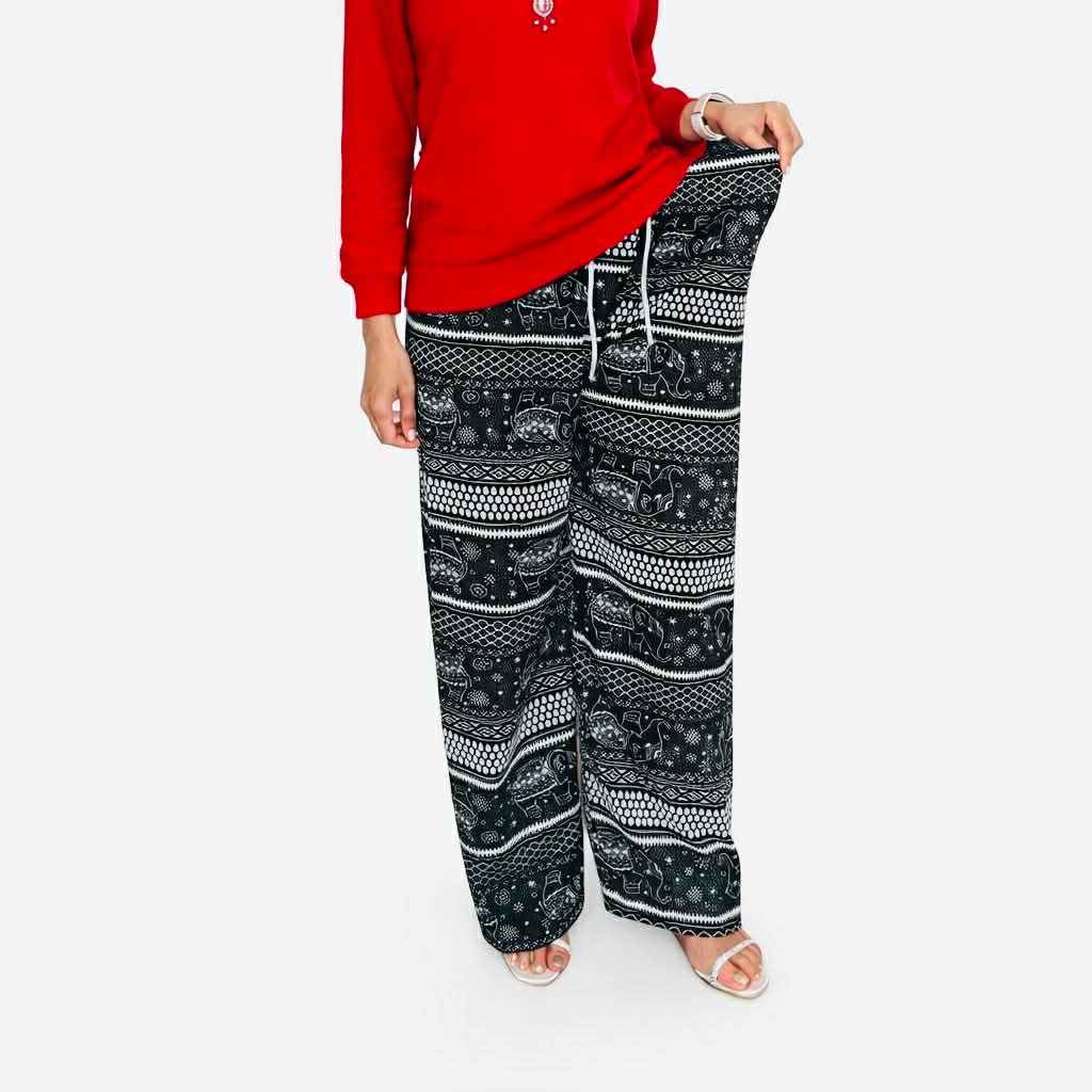 Person wearing a red top and black patterned pants on a white background