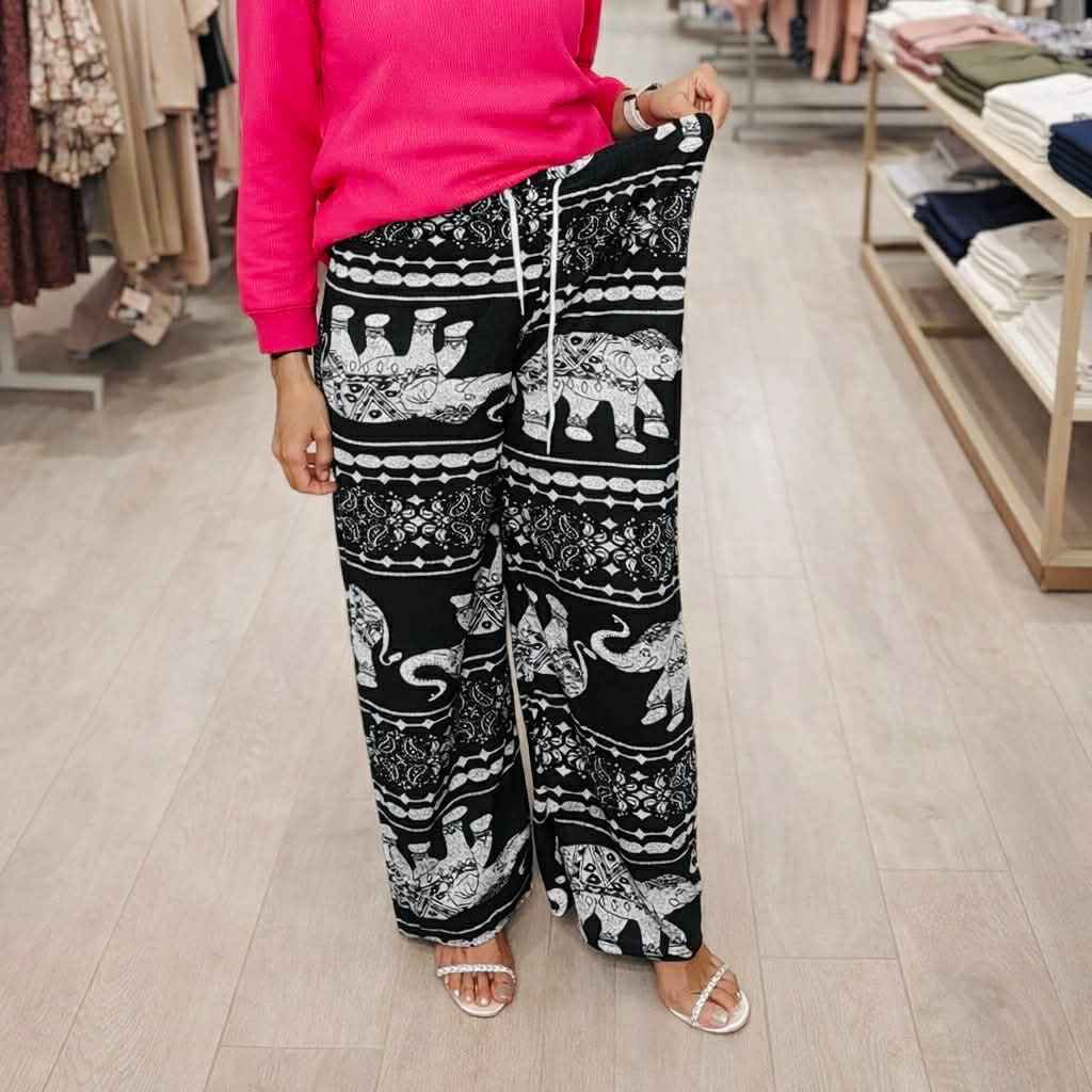 Person wearing black pants with white elephant pattern in a store setting