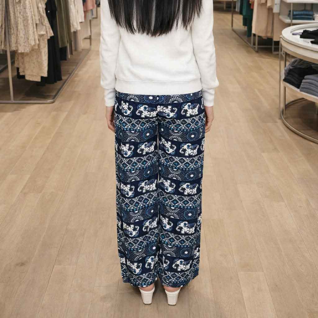 Person wearing blue patterned pants and a white top in a store setting