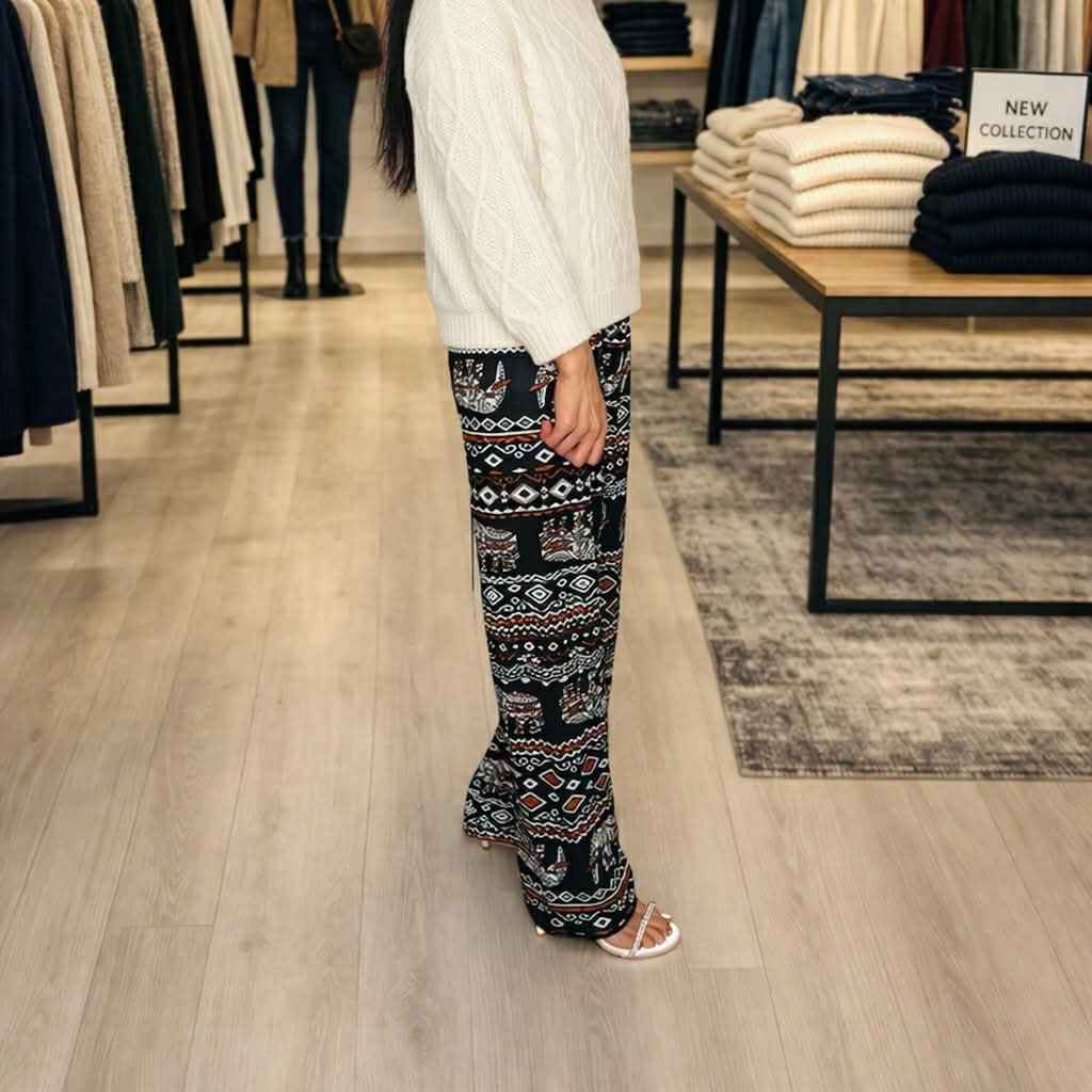 Person wearing patterned pants and a white sweater in a clothing store.