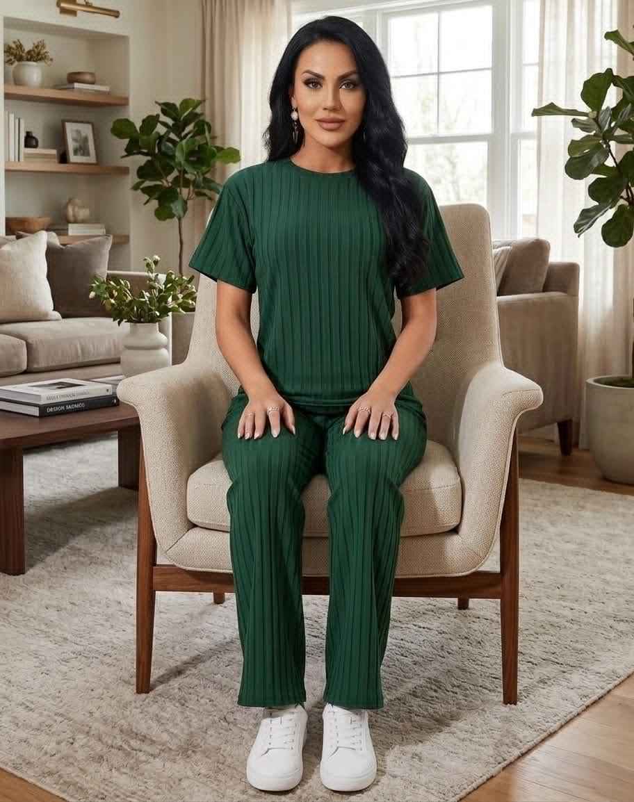 Woman in a green outfit sitting on a chair in a living room.