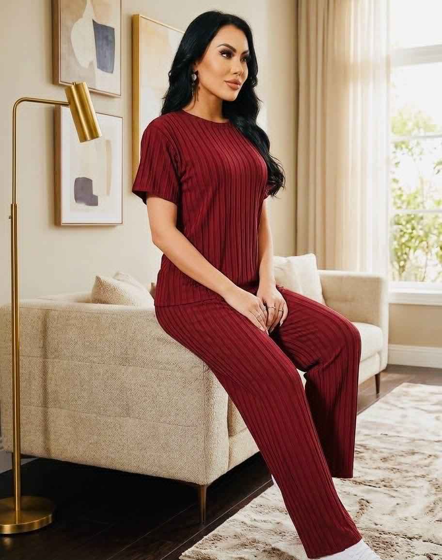 Woman in a red ribbed outfit sitting on a couch in a living room.