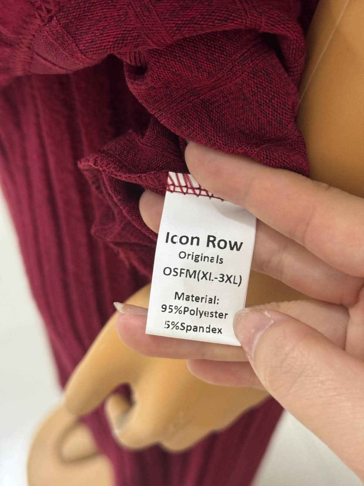 Close-up of a fabric tag on a maroon garment with a hand holding it.